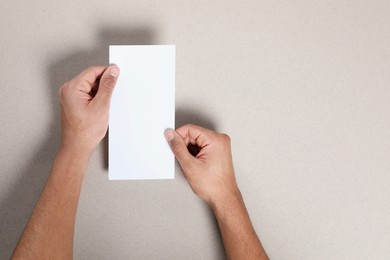 Photo of Man holding flyer on grey background, closeup. Mockup for design