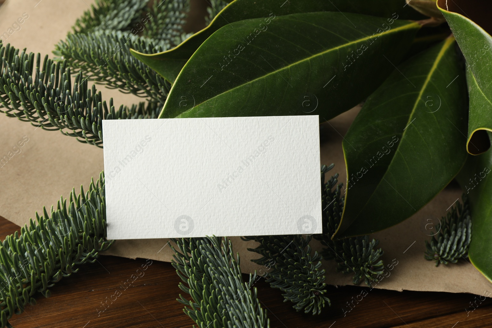 Photo of Blank business card and tree branches on wooden table, closeup. Space for text