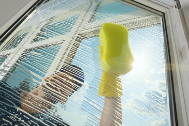 Man cleaning glass with sponge indoors, low angle view