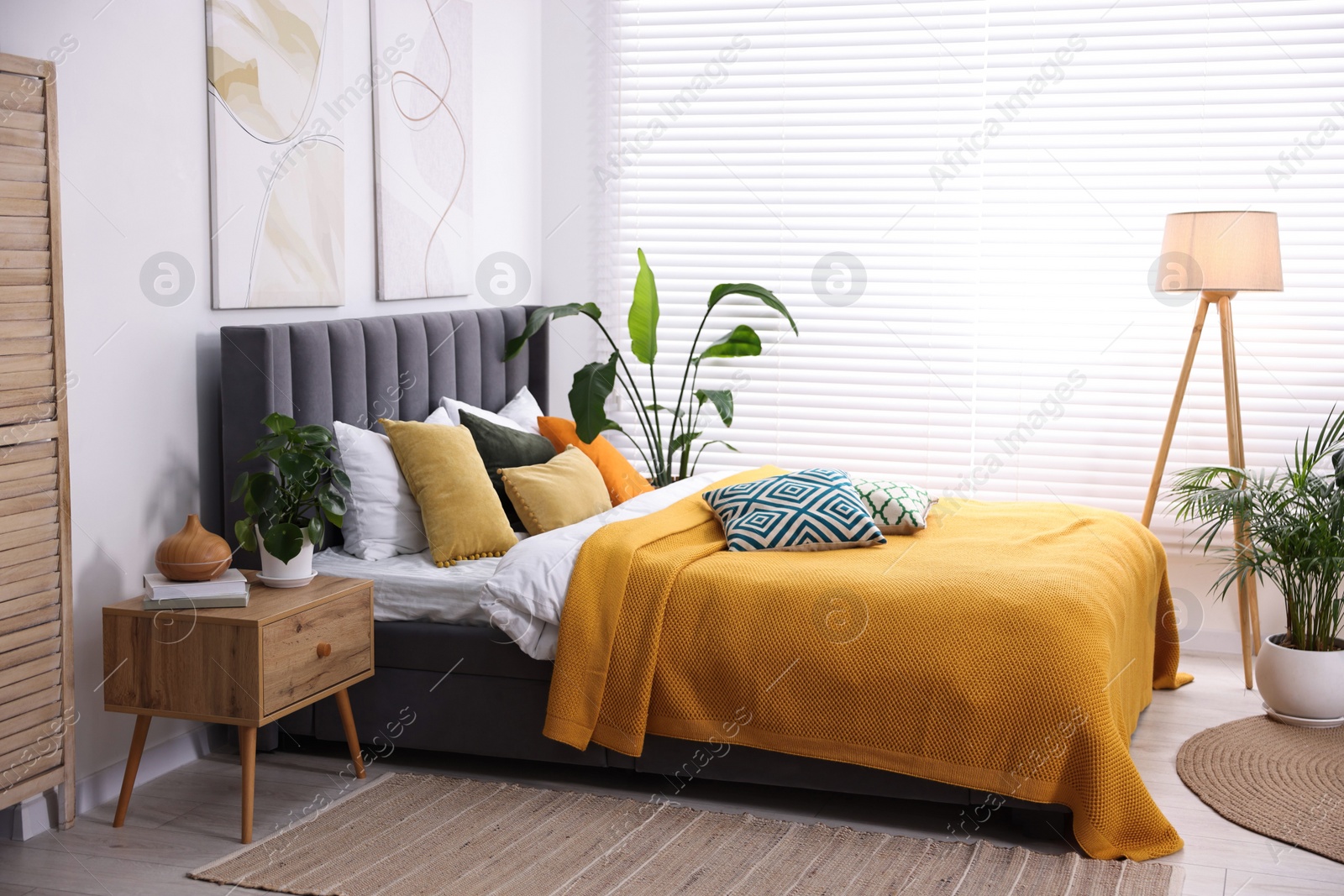 Photo of Bright plaid and colorful pillows on bed in stylish bedroom. Interior design