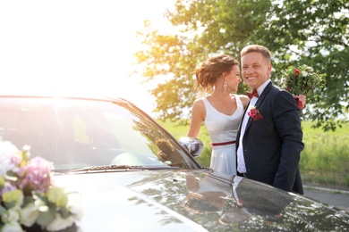 Photo of Happy bride and groom near car outdoors