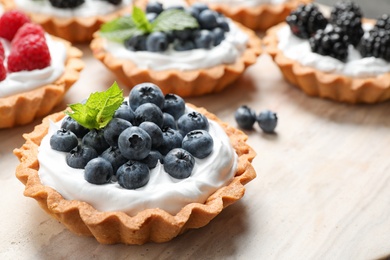 Photo of Different berry tarts on table, closeup. Delicious pastries