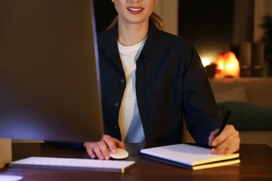 Photo of Home workplace. Woman working on computer at wooden desk indoors, closeup