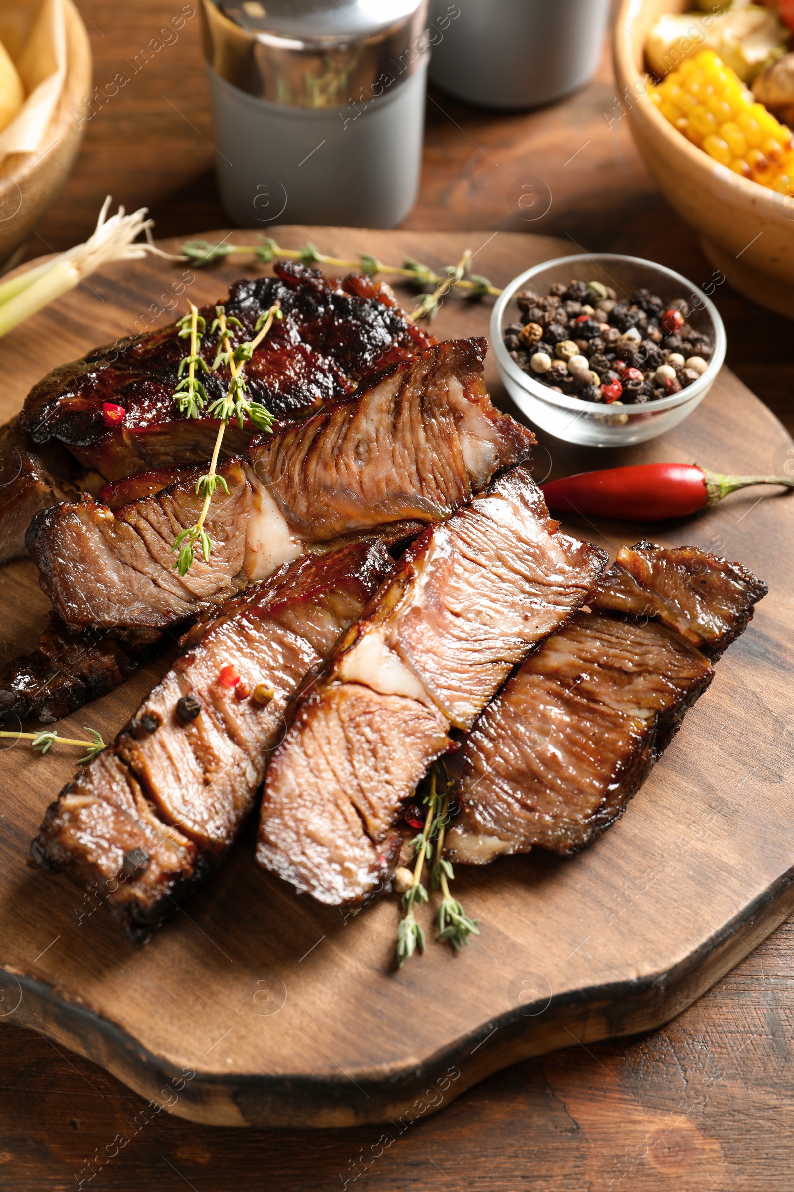 Photo of Serving board with delicious barbecued steak and spices on wooden table