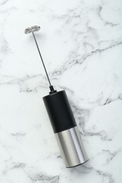 Black milk frother wand on white marble table, top view