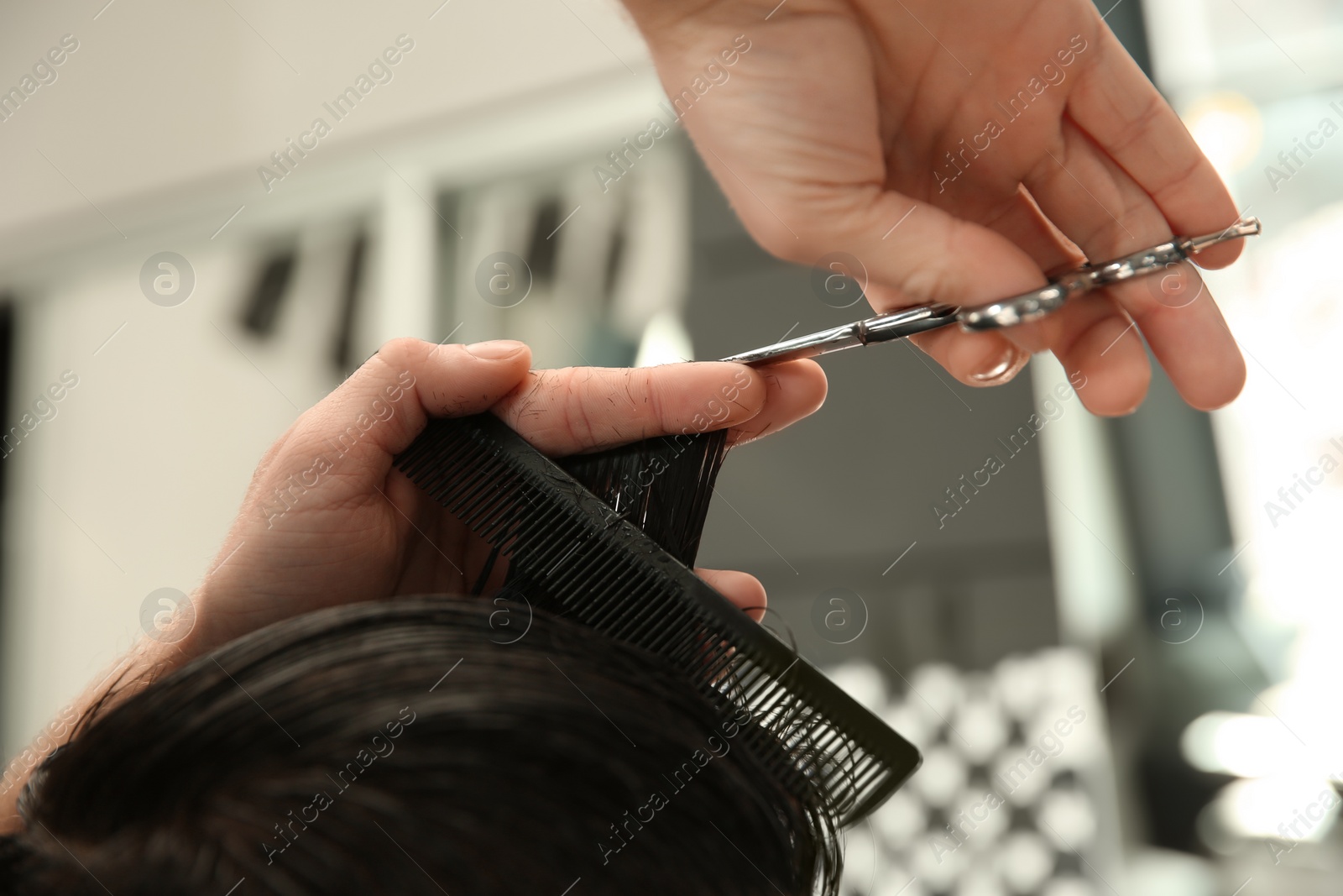 Photo of Professional barber making stylish haircut in salon, closeup