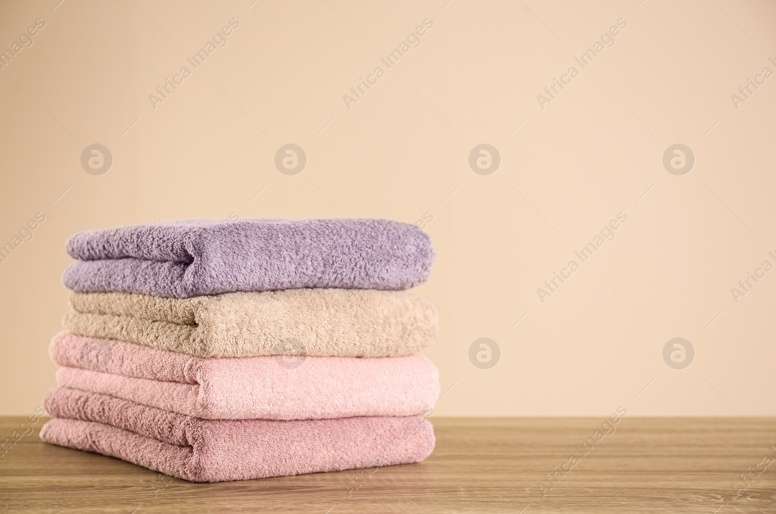 Photo of Stack of clean bath towels on wooden table. Space for text