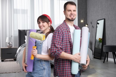 Couple with wallpaper rolls and roller in room