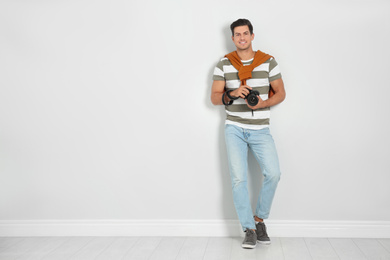 Photo of Professional photographer working near white wall in studio. Space for text