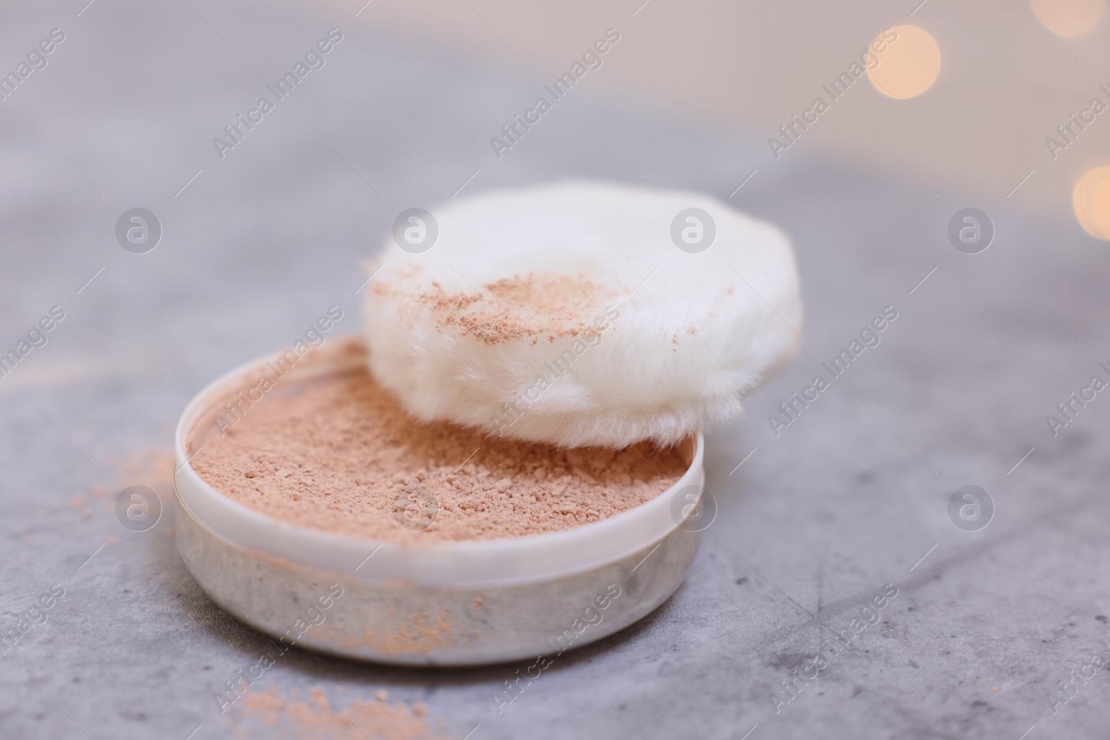 Photo of Face powder and puff applicator on grey textured table, closeup