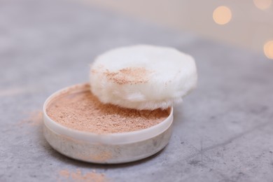 Photo of Face powder and puff applicator on grey textured table, closeup