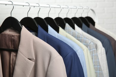 Photo of Dry-cleaning service. Many different clothes hanging on rack against white background, closeup