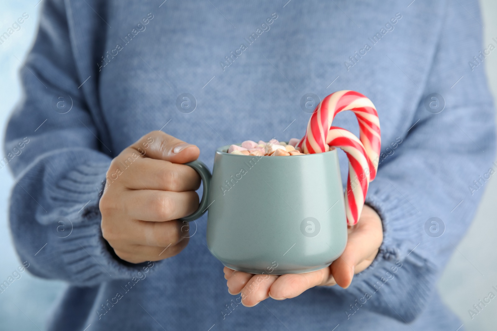 Photo of Woman holding cup of tasty cocoa with marshmallows and Christmas candy canes, closeup