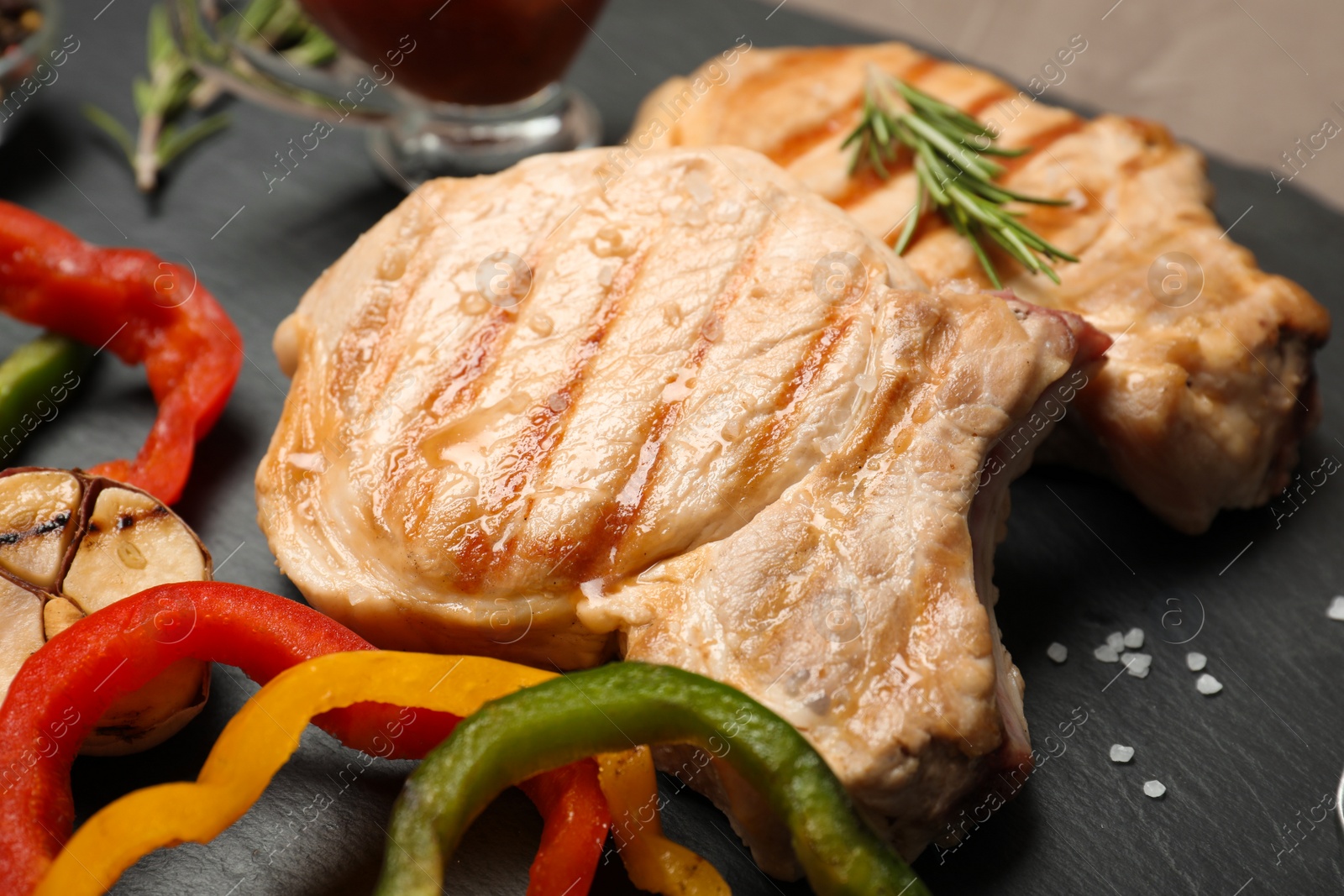 Photo of Grilled meat served with garnish on slate plate, closeup