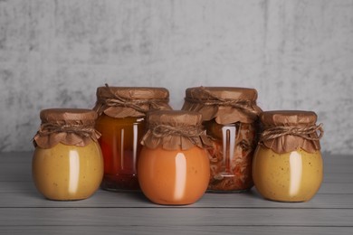 Glass jars with different preserved products on wooden table