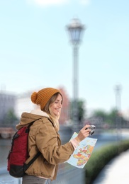 Image of Happy traveler with camera and map in foreign city. Vacation trip