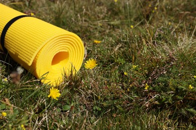 Rolled yellow soft sleeping pad on grass, space for text