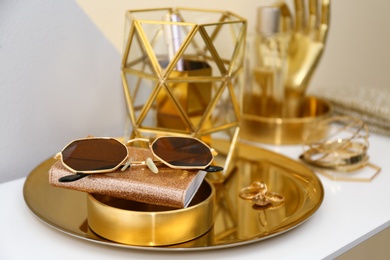 Gold tray with notebook, glasses and accessories on dressing table. Space for text