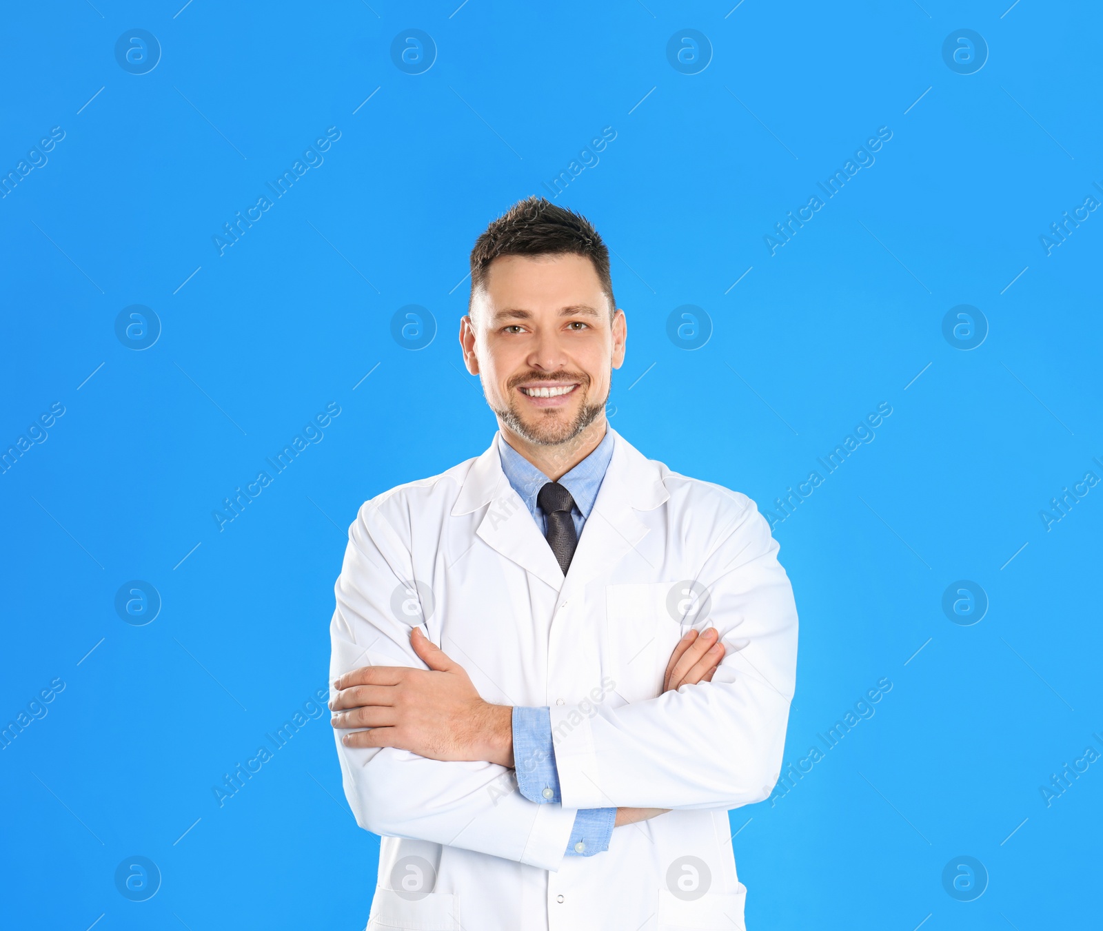 Photo of Happy man in lab coat on light blue background