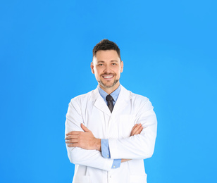 Happy man in lab coat on light blue background
