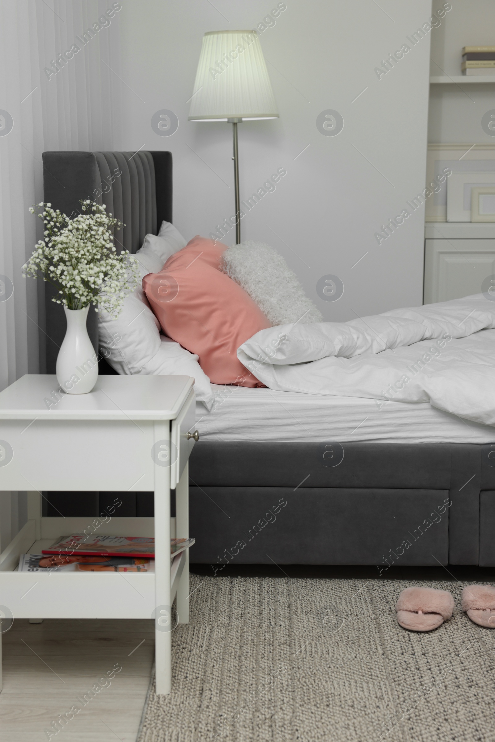 Photo of Stylish bedroom interior with comfortable bed, nightstand and lamp