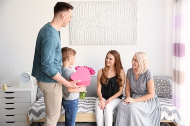 Photo of Man and little boy congratulating women at home