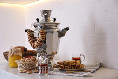 Traditional Russian samovar with treats on white table