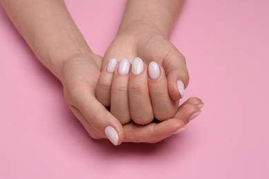 Photo of Woman showing her manicured hands with white nail polish on pink background, closeup