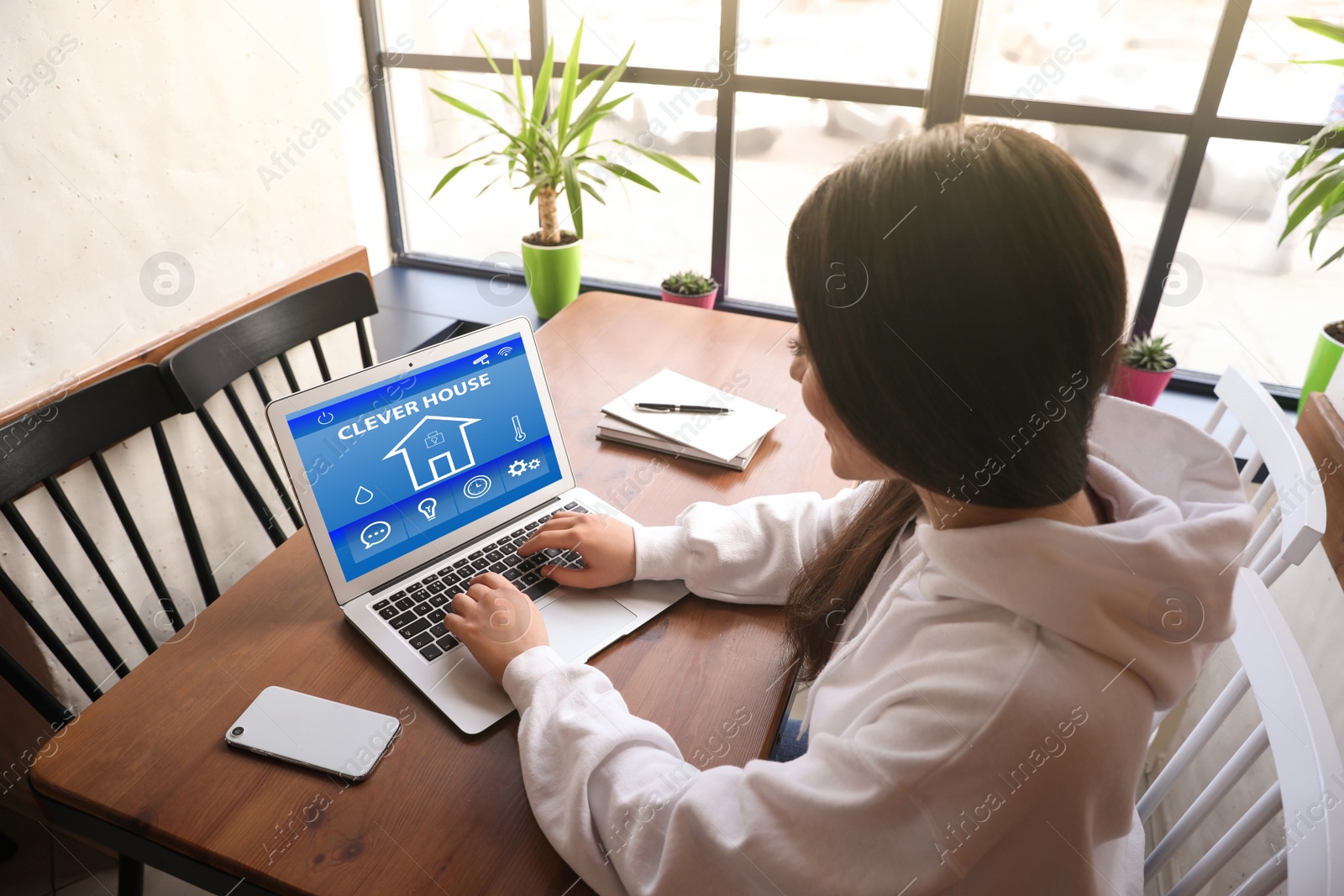 Image of Young woman using home security app indoors