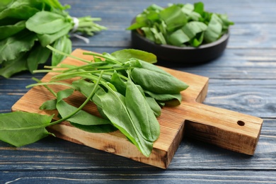 Photo of Fresh green sorrel leaves on blue wooden table, closeup