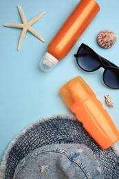 Photo of Flat lay composition with bottles of sunscreen on light blue background