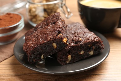 Photo of Delicious chocolate brownies with nuts on wooden table, closeup