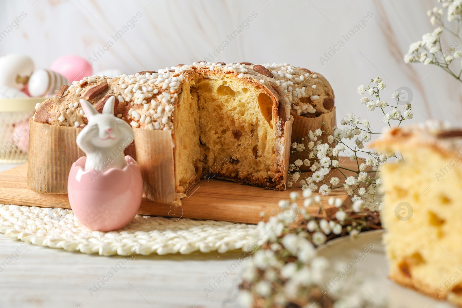 Photo of Delicious Italian Easter dove cake (traditional Colomba di Pasqua) and festive decor on white wooden table