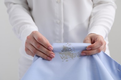 Woman holding shirt with stain against light background, closeup