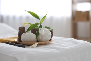 Spa stones, flowers, towel and herbal bags on massage table indoors