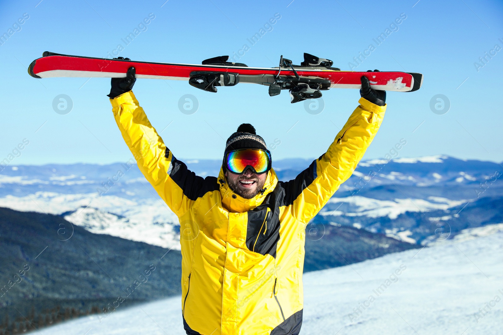 Photo of Happy man with ski equipment in mountains. Winter vacation