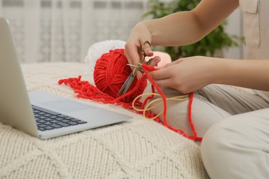 Photo of Woman learning to knit with online course at home, closeup. Handicraft hobby