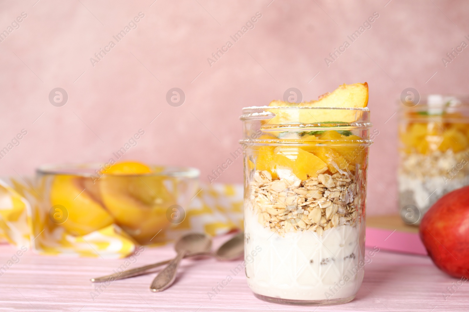 Photo of Tasty peach dessert with yogurt and granola served on pink wooden table. Space for text