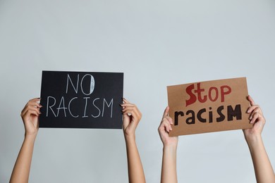 Photo of Women holding signs on grey background, closeup. Racism concept