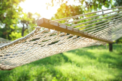 Comfortable net hammock hanging in green garden, closeup