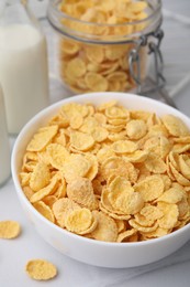 Photo of Tasty crispy corn flakes in bowl on white table, closeup. Breakfast cereal