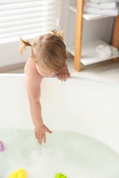 Cute little girl near tub in bathroom
