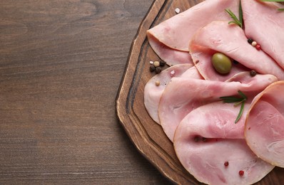 Photo of Slices of delicious ham with rosemary and olive on wooden table, top view. Space for text
