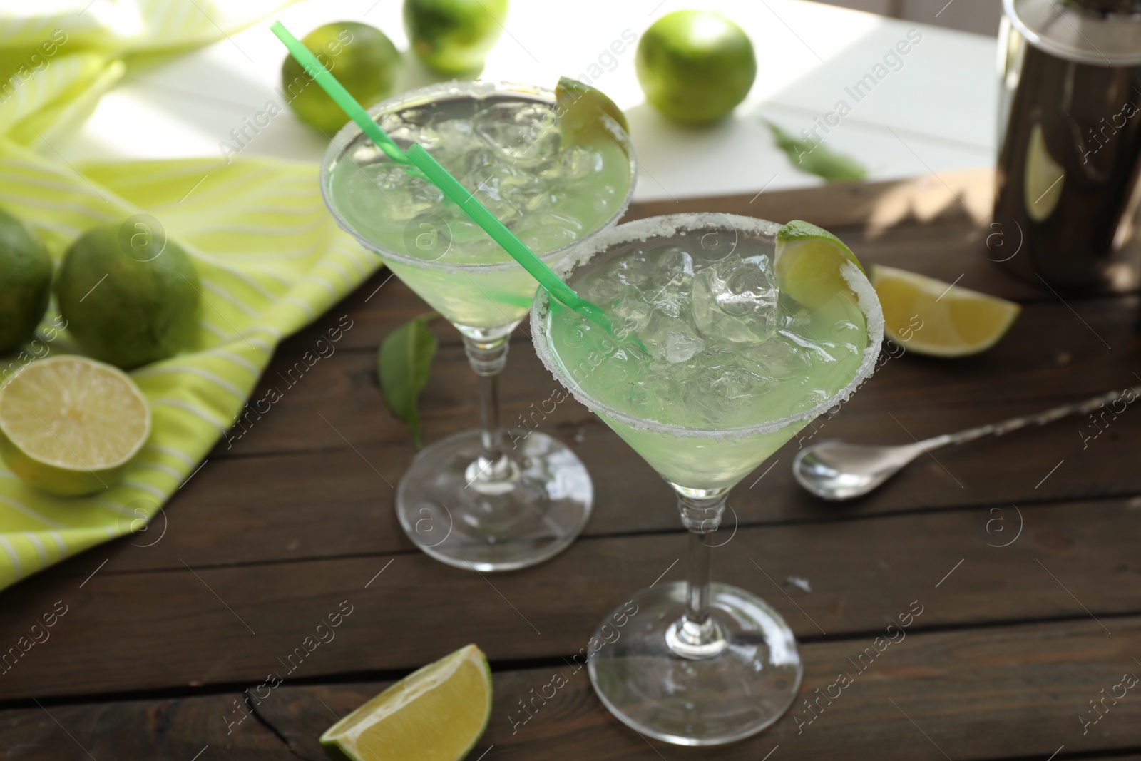 Photo of Delicious Margarita cocktail in glasses and lime on wooden table, closeup