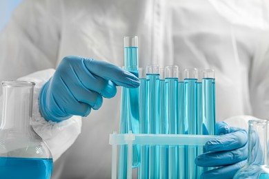 Scientist taking test tube with light blue liquid, closeup