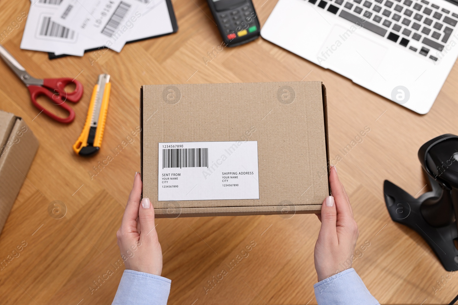 Photo of Post office worker packing parcel at wooden table, top view