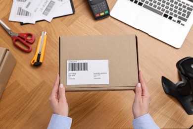 Post office worker packing parcel at wooden table, top view