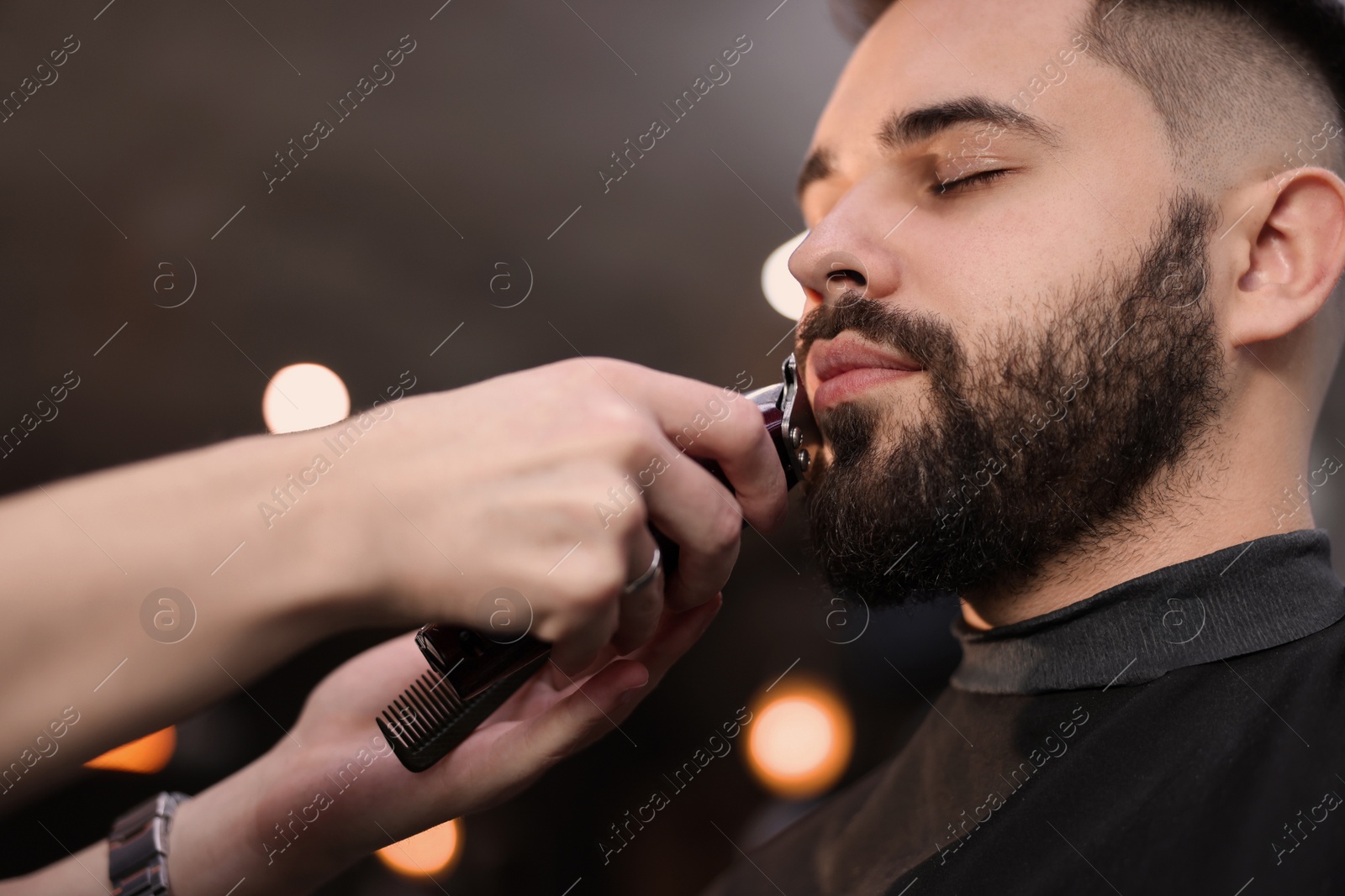 Photo of Professional hairdresser working with client in barbershop, closeup