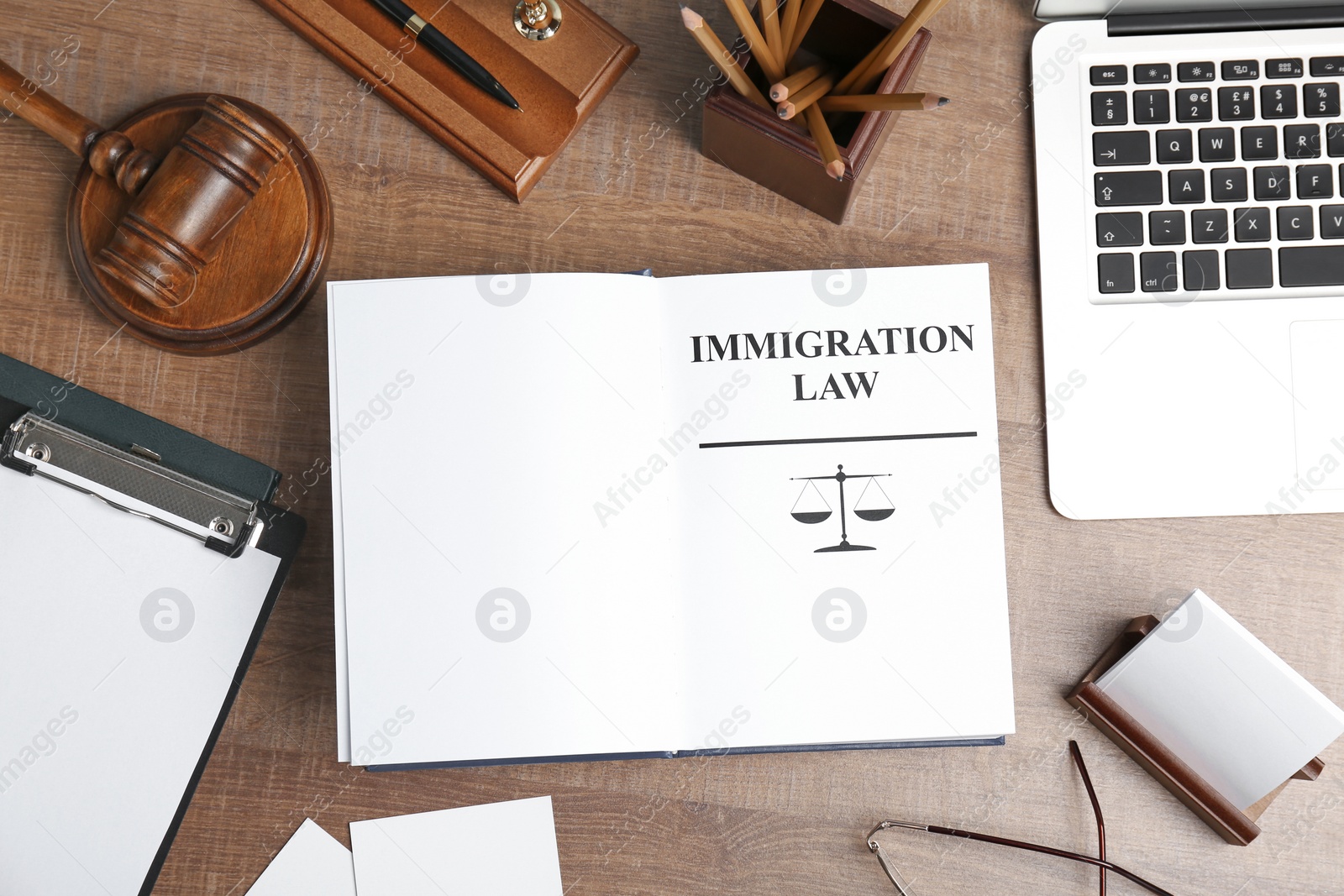 Photo of Flat lay composition with book, gavel and laptop on wooden background. Immigration law concept