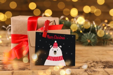 Image of Greeting card with text Merry Christmas and gift on wooden table